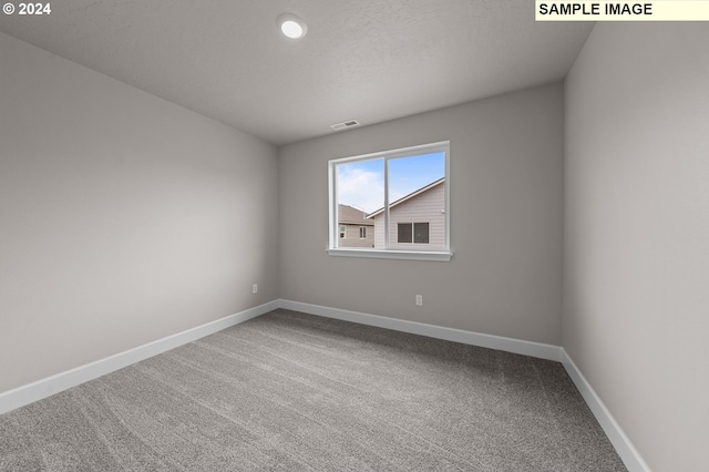 carpeted spare room with visible vents and baseboards