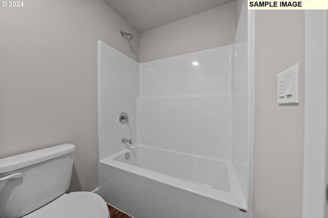 bathroom featuring hardwood / wood-style flooring, shower / bath combination, and toilet