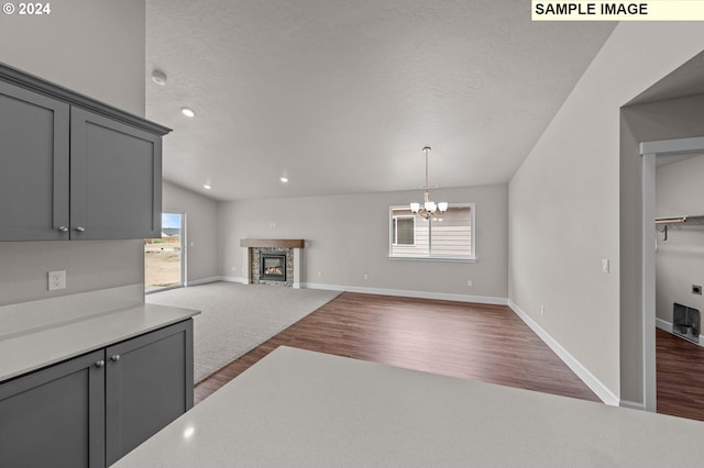 kitchen with dark wood-type flooring, a stone fireplace, gray cabinets, a textured ceiling, and a notable chandelier