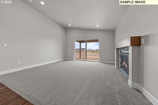 unfurnished living room featuring carpet floors, a fireplace, and vaulted ceiling