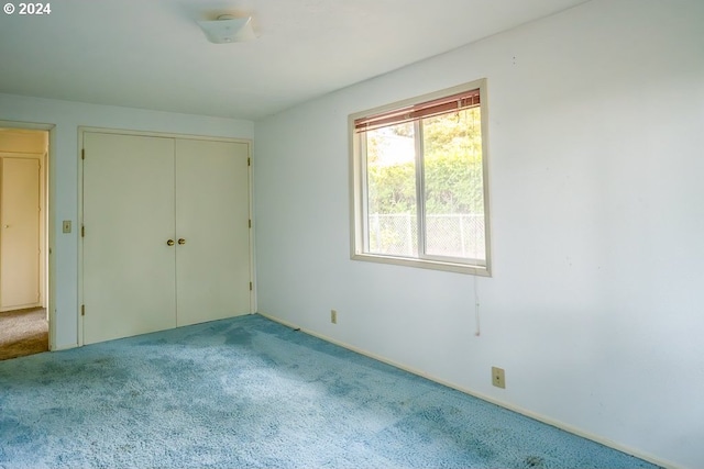 unfurnished bedroom featuring light carpet and a closet