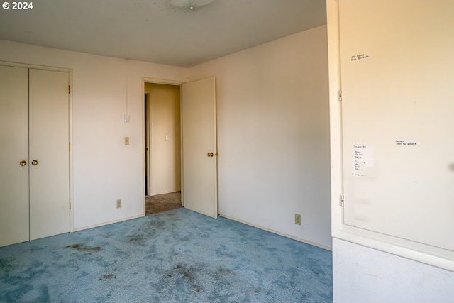 unfurnished bedroom featuring light carpet and a closet