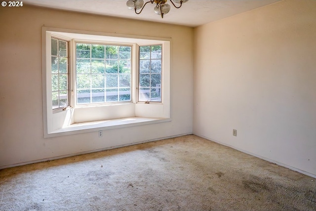 carpeted empty room with an inviting chandelier