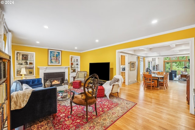 living room with beam ceiling, ornamental molding, and light hardwood / wood-style floors