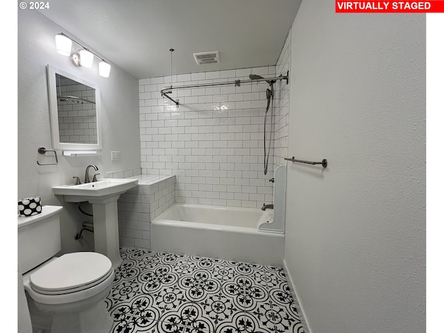 bathroom featuring tile floors, toilet, and tiled shower / bath combo