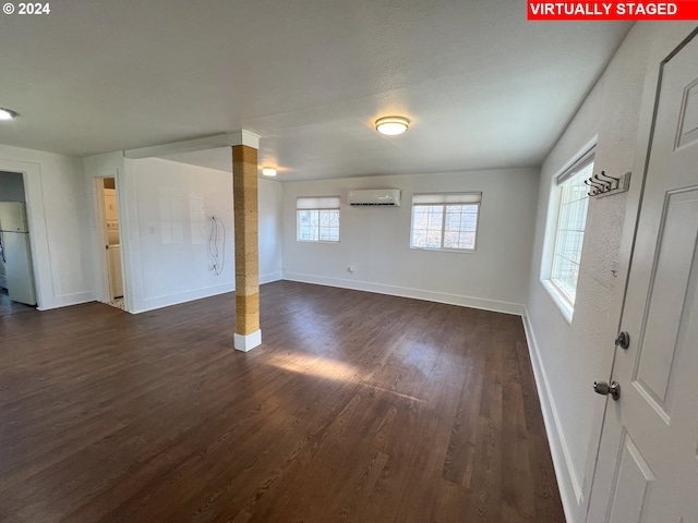 empty room featuring an AC wall unit and dark hardwood / wood-style floors