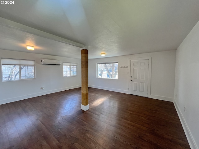 basement with dark wood-type flooring and a wall unit AC