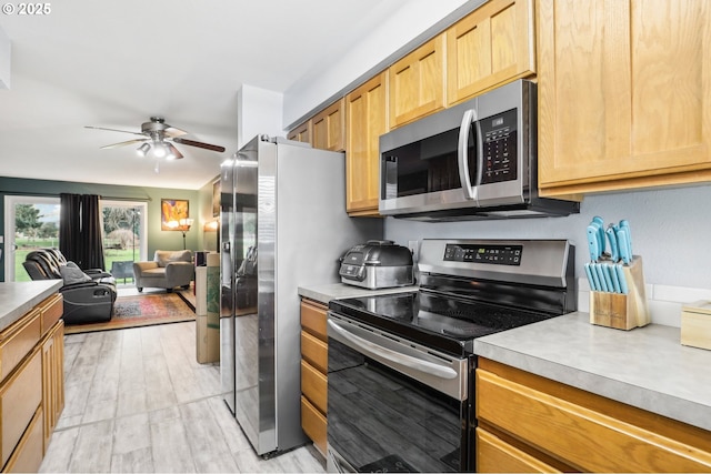 kitchen featuring stainless steel appliances, ceiling fan, and light hardwood / wood-style floors