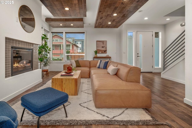 living room featuring recessed lighting, wood finished floors, a tile fireplace, baseboards, and stairs