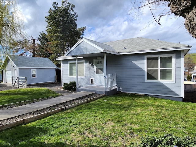 view of front of property featuring a front yard, an outdoor structure, and a garage