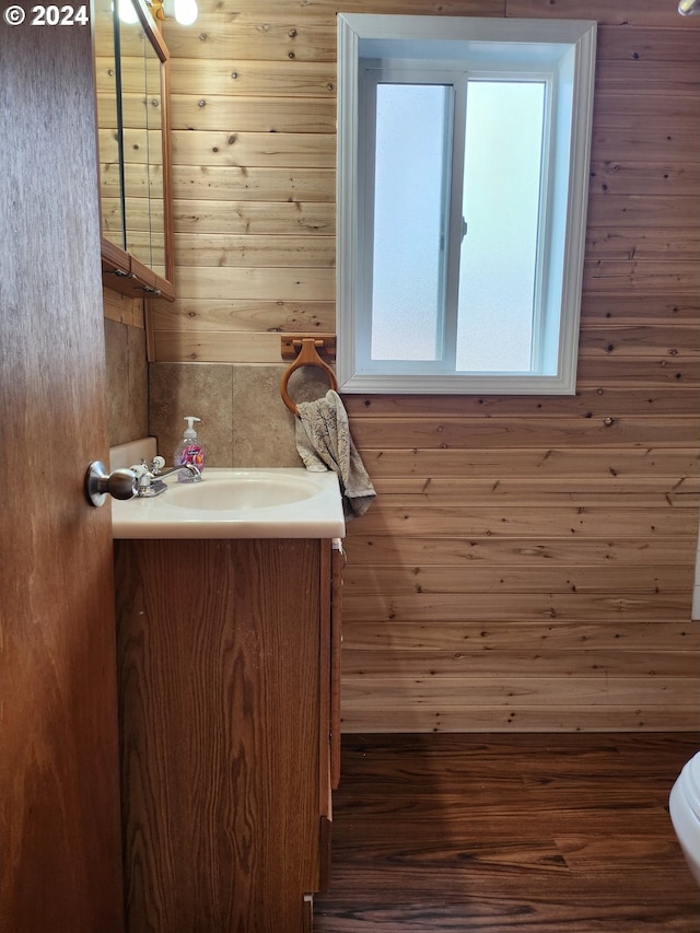 bathroom featuring wooden walls, toilet, vanity, and wood-type flooring