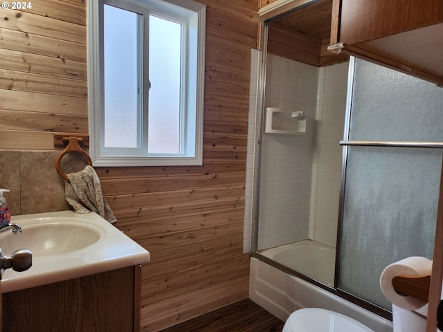 full bathroom with toilet, wood walls, and bath / shower combo with glass door