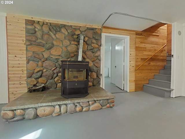 details with wooden walls, a wood stove, and concrete flooring