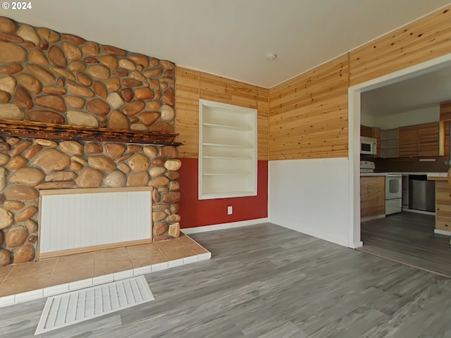 unfurnished living room with wooden walls, dark hardwood / wood-style floors, and radiator