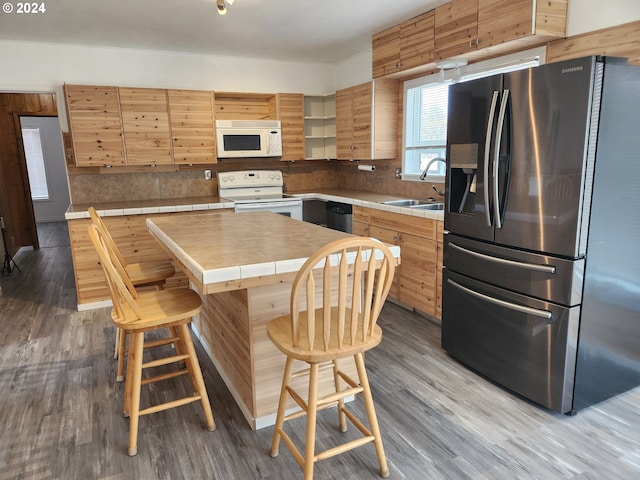 kitchen featuring white appliances, light hardwood / wood-style flooring, sink, and tile counters