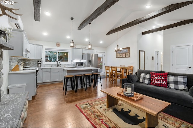 living room featuring beam ceiling, sink, high vaulted ceiling, and dark wood-type flooring