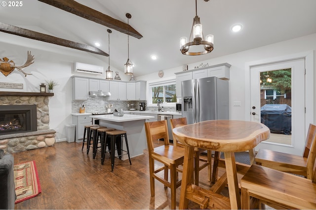 dining space featuring a wall mounted air conditioner, dark hardwood / wood-style flooring, sink, a fireplace, and vaulted ceiling with beams