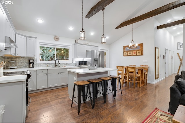 kitchen featuring backsplash, sink, beamed ceiling, a kitchen island, and stainless steel appliances