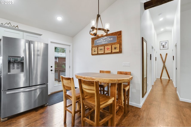 dining area with dark hardwood / wood-style floors, lofted ceiling, and an inviting chandelier