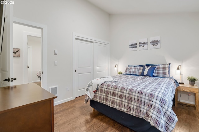 bedroom with wood-type flooring, a closet, and lofted ceiling