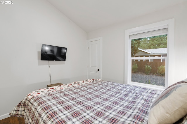 bedroom with multiple windows, hardwood / wood-style floors, and vaulted ceiling