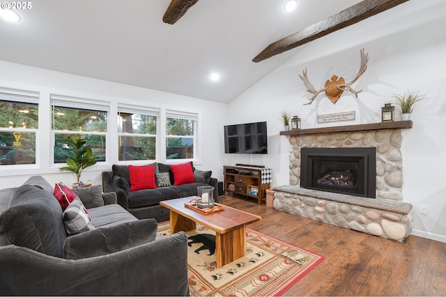 living room featuring hardwood / wood-style floors, lofted ceiling with beams, and a stone fireplace