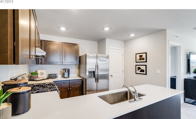 kitchen featuring a textured ceiling, sink, stainless steel fridge, kitchen peninsula, and stove