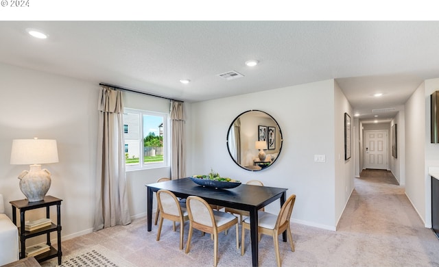 carpeted dining space featuring a textured ceiling