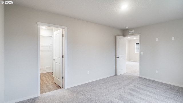 unfurnished bedroom featuring a closet, light colored carpet, and a spacious closet