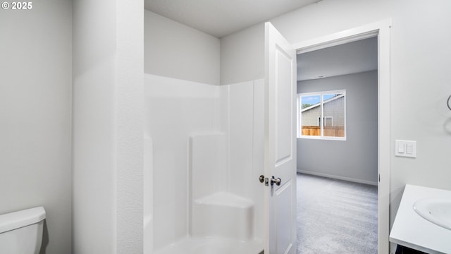 bathroom featuring toilet, vanity, and a shower