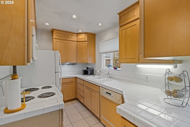 kitchen featuring light tile patterned flooring, white appliances, tile counters, and sink