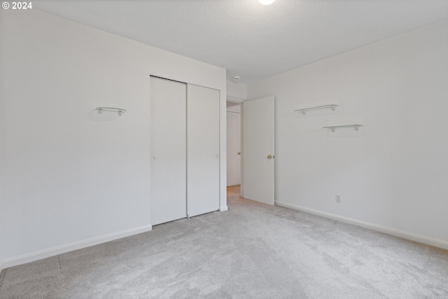 unfurnished bedroom with a closet, light colored carpet, and a textured ceiling