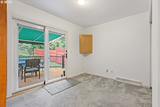 doorway to outside with light colored carpet, a textured ceiling, and a baseboard heating unit