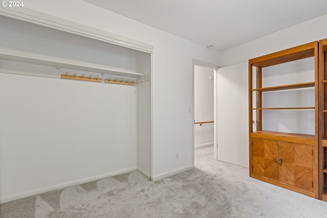 unfurnished bedroom with light colored carpet and a closet