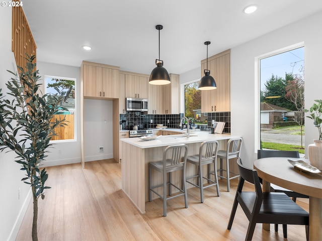 kitchen featuring kitchen peninsula, light brown cabinets, stainless steel appliances, and a wealth of natural light