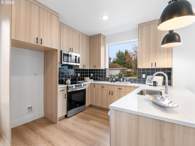 kitchen featuring pendant lighting, light brown cabinets, backsplash, appliances with stainless steel finishes, and light hardwood / wood-style floors