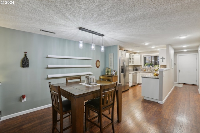 dining area featuring sink, dark hardwood / wood-style flooring, and a textured ceiling