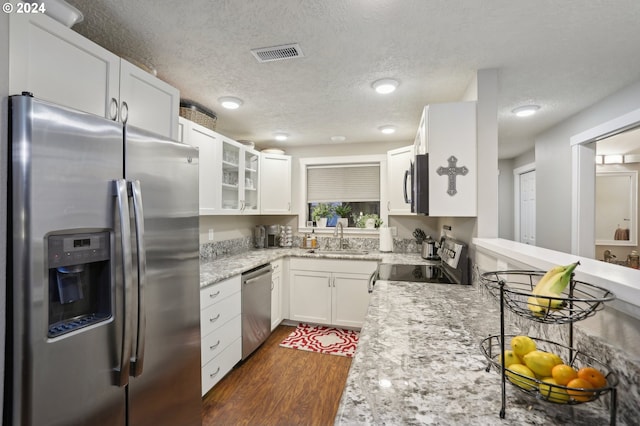 kitchen featuring sink, dark hardwood / wood-style floors, light stone counters, white cabinetry, and stainless steel appliances