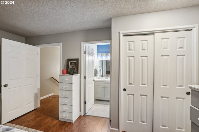 bedroom with connected bathroom, a closet, dark hardwood / wood-style flooring, and a textured ceiling