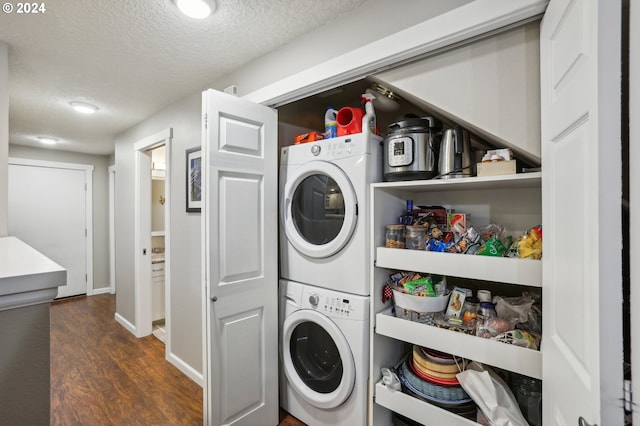 laundry area featuring a textured ceiling, stacked washing maching and dryer, and dark hardwood / wood-style floors