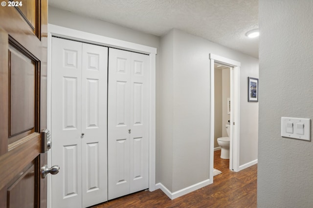 hall with a textured ceiling and dark hardwood / wood-style floors