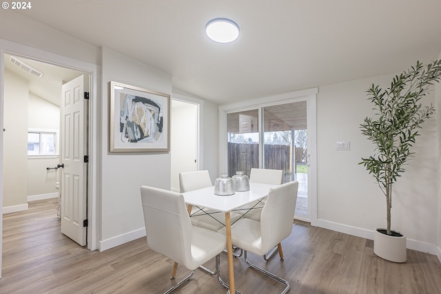 dining room with lofted ceiling and light wood-type flooring