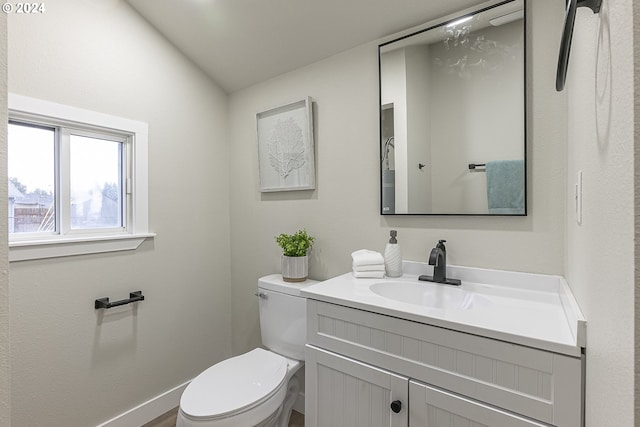 bathroom featuring toilet, vanity, and vaulted ceiling