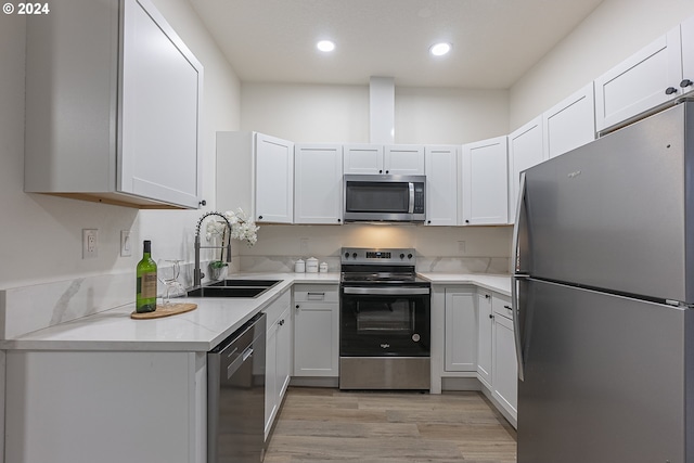 kitchen featuring appliances with stainless steel finishes, light wood-type flooring, white cabinetry, and sink