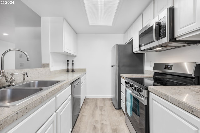 kitchen with appliances with stainless steel finishes, light wood-type flooring, white cabinetry, and sink