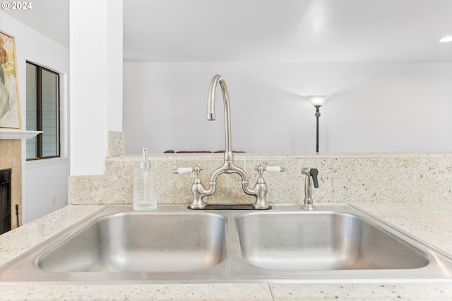 details featuring light stone countertops, sink, and a tiled fireplace