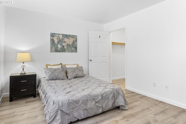 bedroom with light hardwood / wood-style flooring, a spacious closet, and a closet