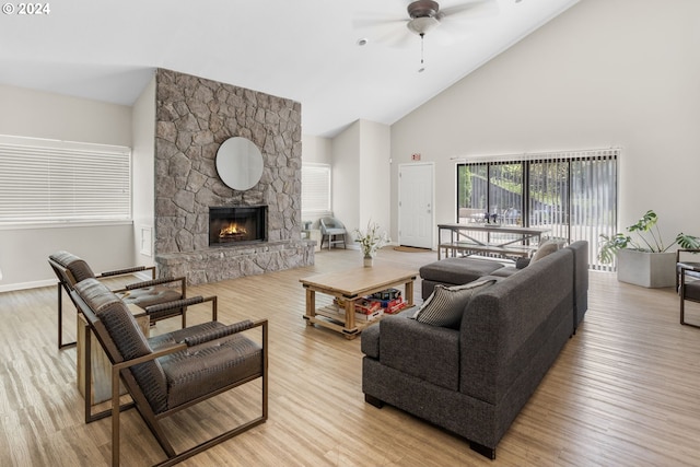 living room featuring a stone fireplace, ceiling fan, light hardwood / wood-style flooring, and high vaulted ceiling