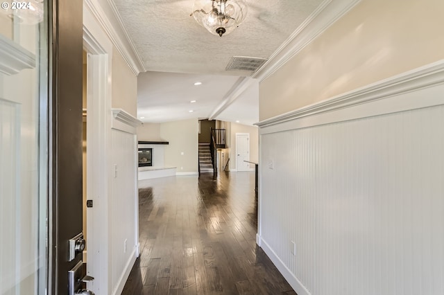 hall with dark hardwood / wood-style flooring, crown molding, a textured ceiling, and vaulted ceiling