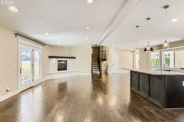 unfurnished living room with vaulted ceiling with beams, dark wood-type flooring, and a healthy amount of sunlight